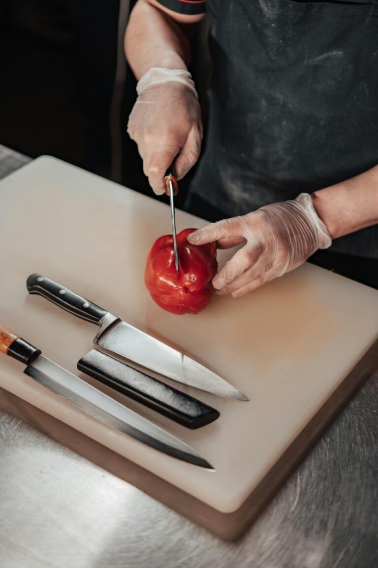 assorted kitchen knives on a cutting board as chef slices a tomato
