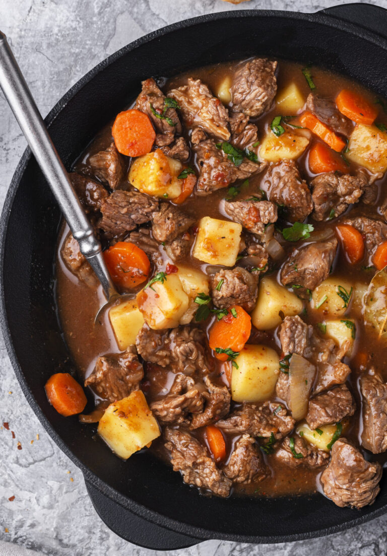 beef stew with carrots, beef and potatoes in a cast iron pot on a table