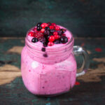 A small glass mug filled with berry smoothie, topped wth fresh berries.