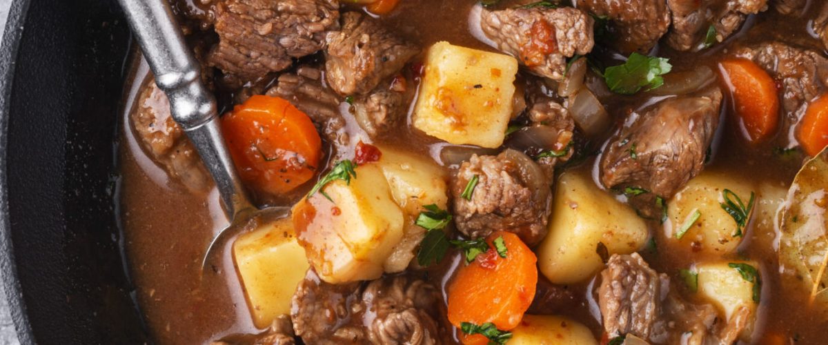 beef stew with carrots, beef and potatoes in a cast iron pot on a table