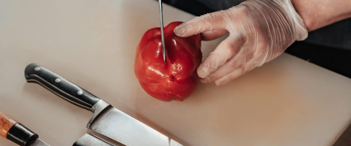 assorted kitchen knives on a cutting board as chef slices a tomato