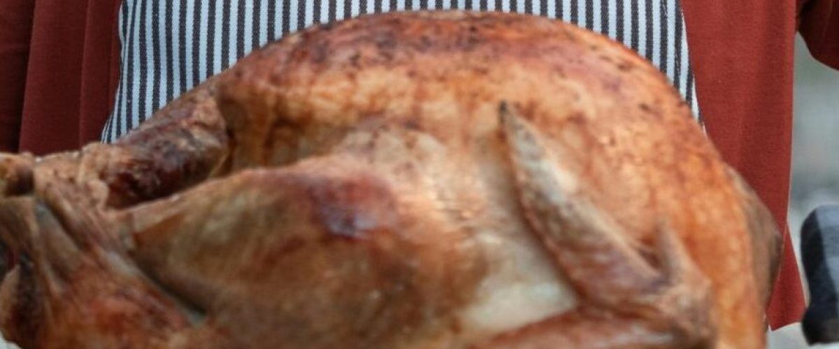 woman holding a golden roasted turkey